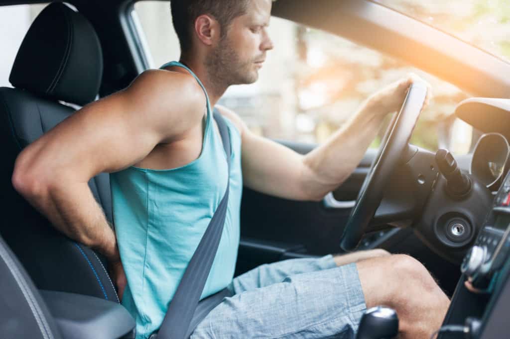 man with back pain in a car driving