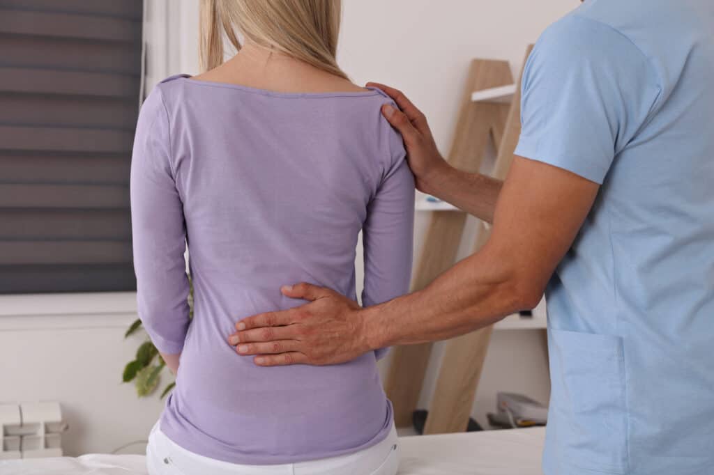 Woman having Chiropractic Back Adjustment. Osteopathy, Physiotherapy, Sport Injury Rehabilitation Concept