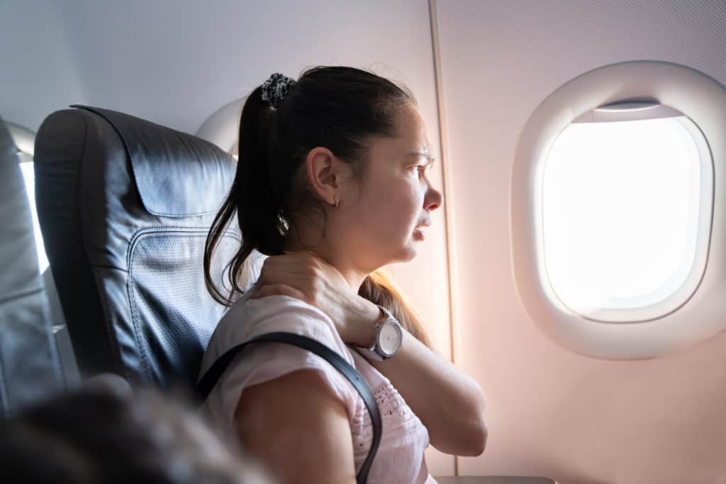 woman with neck pain while travelling on a plane