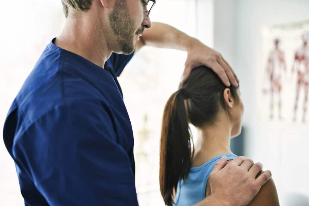 A Male Physical Therapist Stretching a Female Patient neck