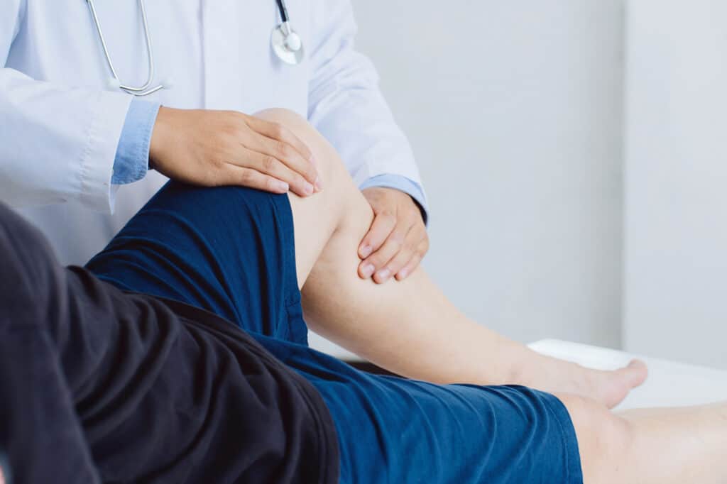 physical therapist looking at man's knee