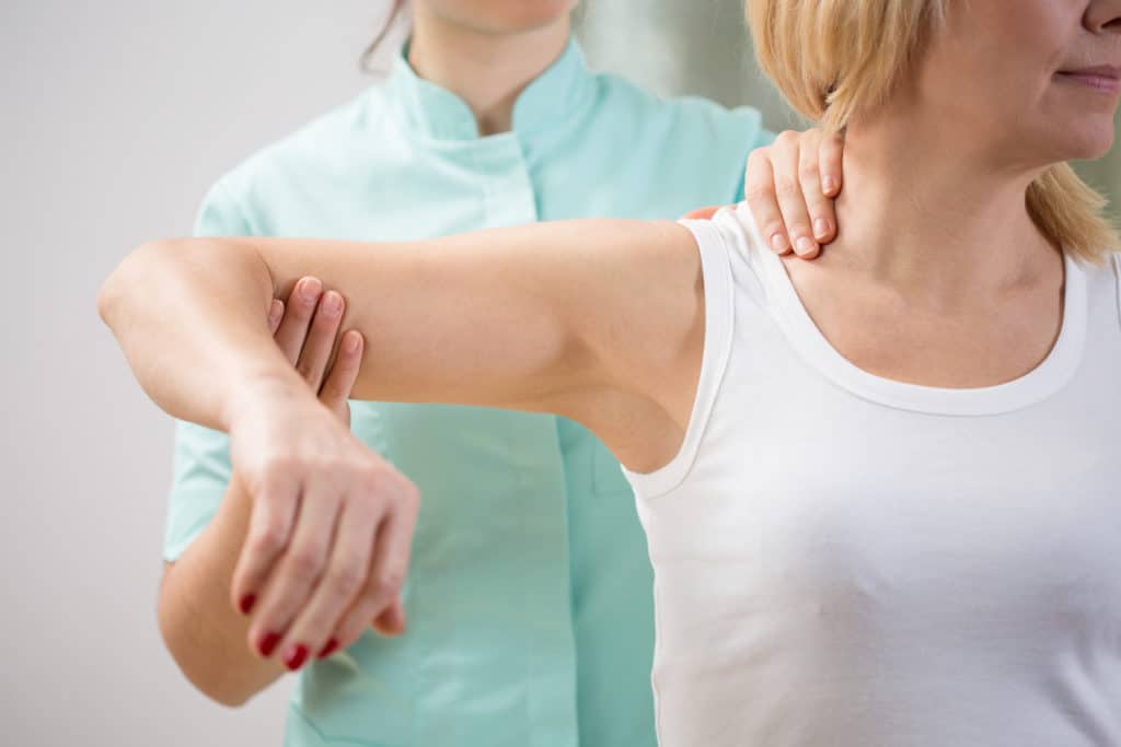 Physical therapist diagnosing patient with shoulder pain