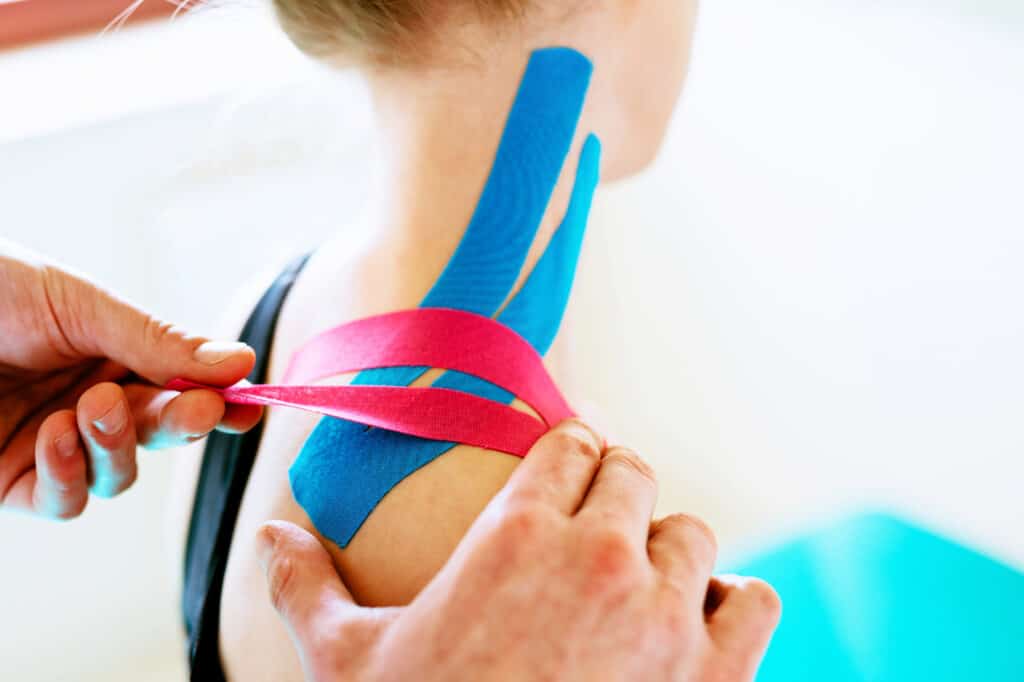 Kinesiotaping. Physical therapist applying tape to patient shoulder