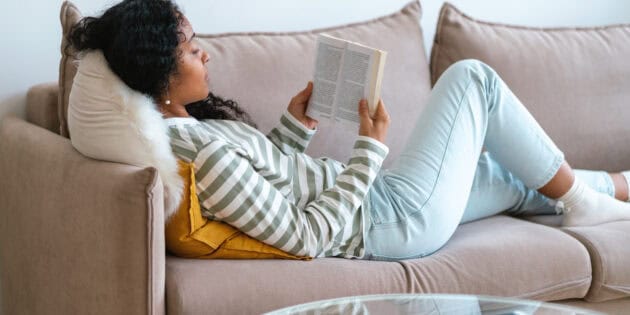 a woman lying on a couch reading a book