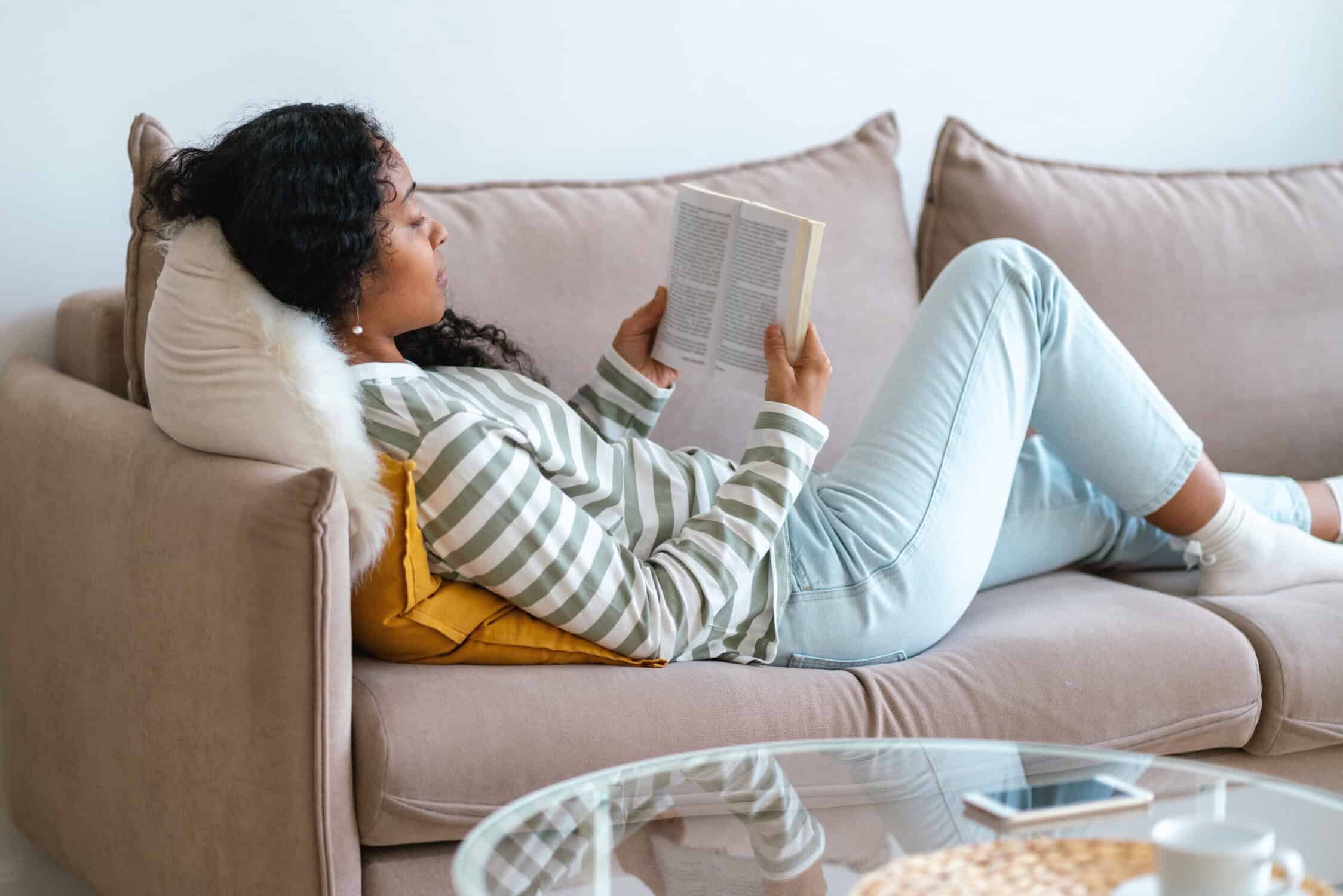 a woman lying on a couch reading a book