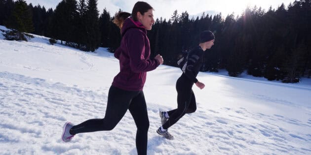 a man and woman running in snow