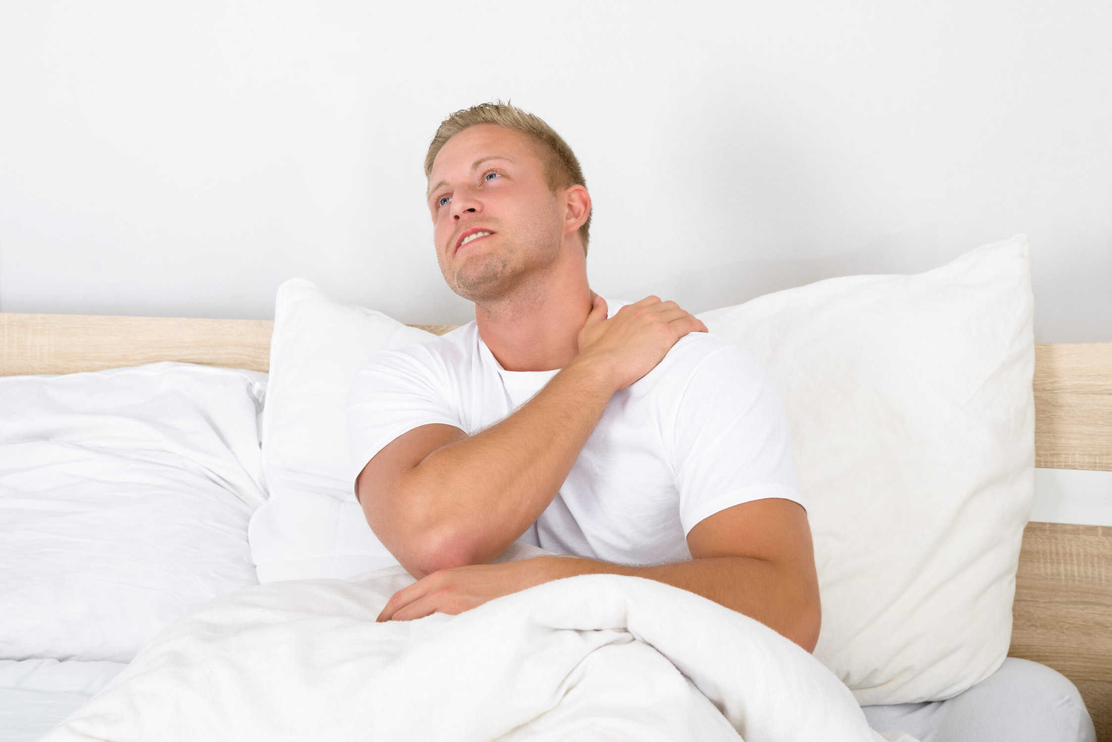 man suffering with shoulder pain in bed